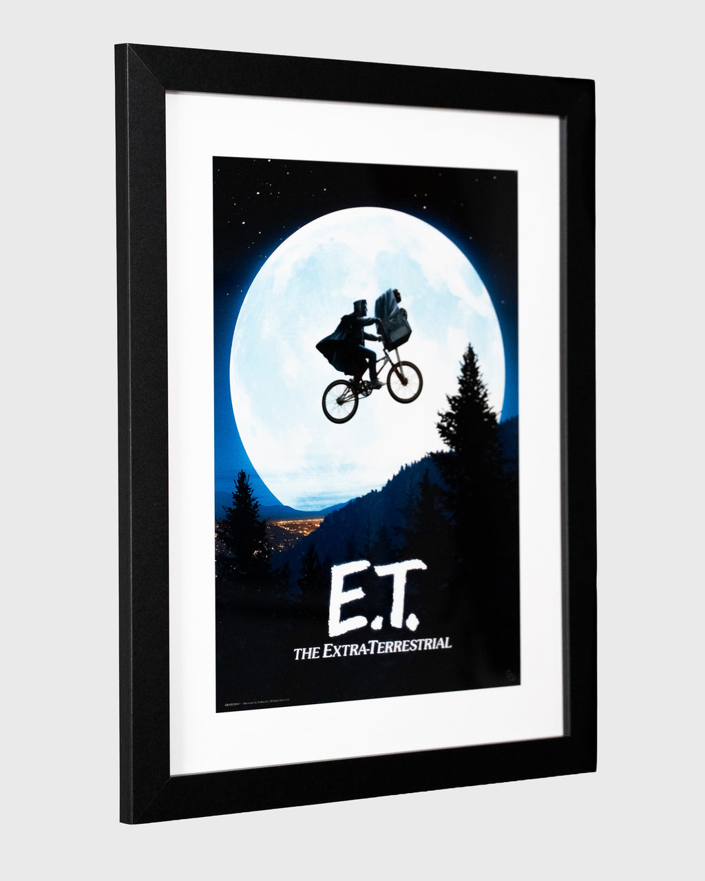 Plakat filmowy E.T. – The Extra-Terrestrial w czarnej ramie, ujęcie pod kątem