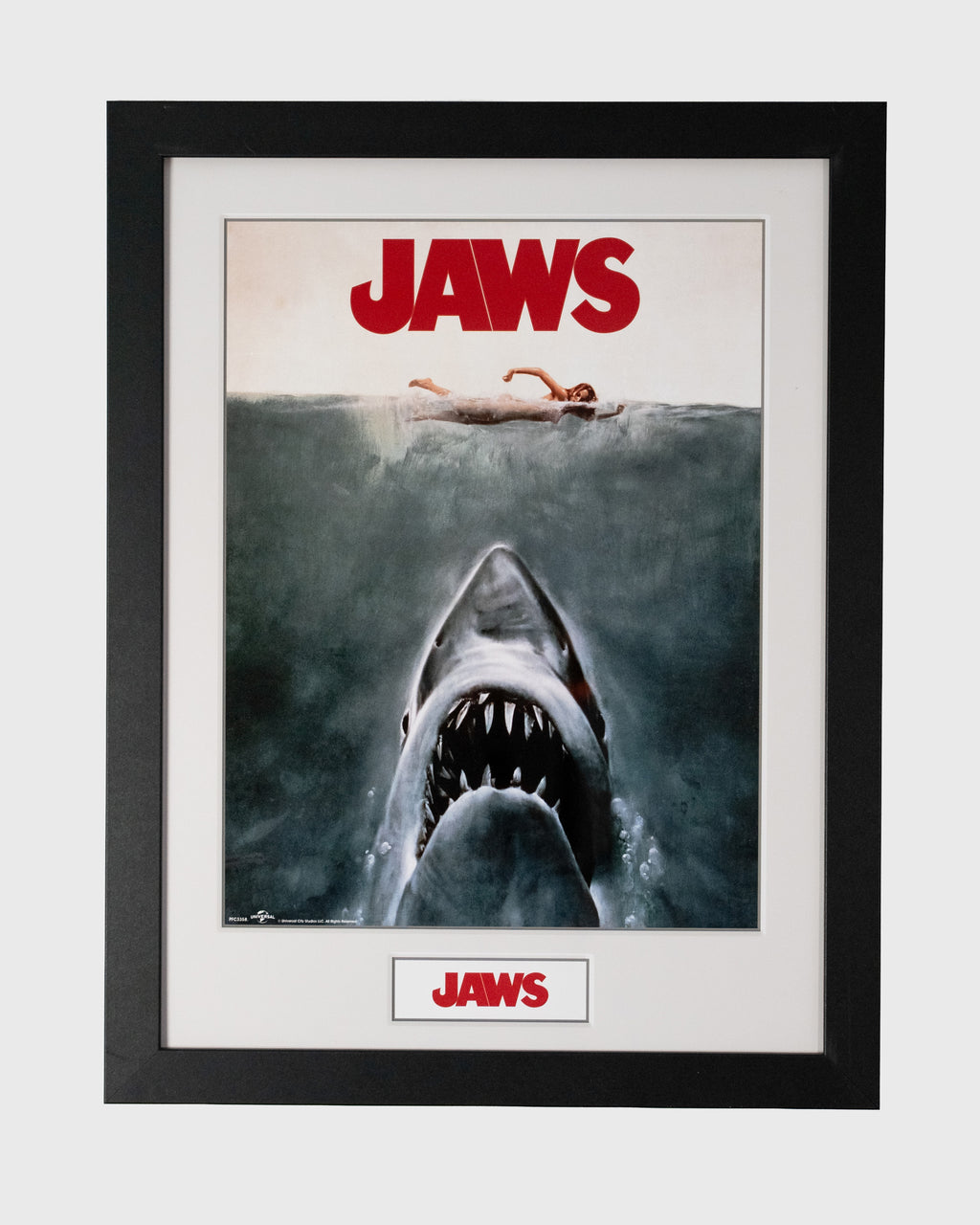 Plakat Jaws w czarnej ramie z rekinem wynurzającym się spod wody