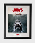 Plakat Jaws w czarnej ramie z rekinem wynurzającym się spod wody