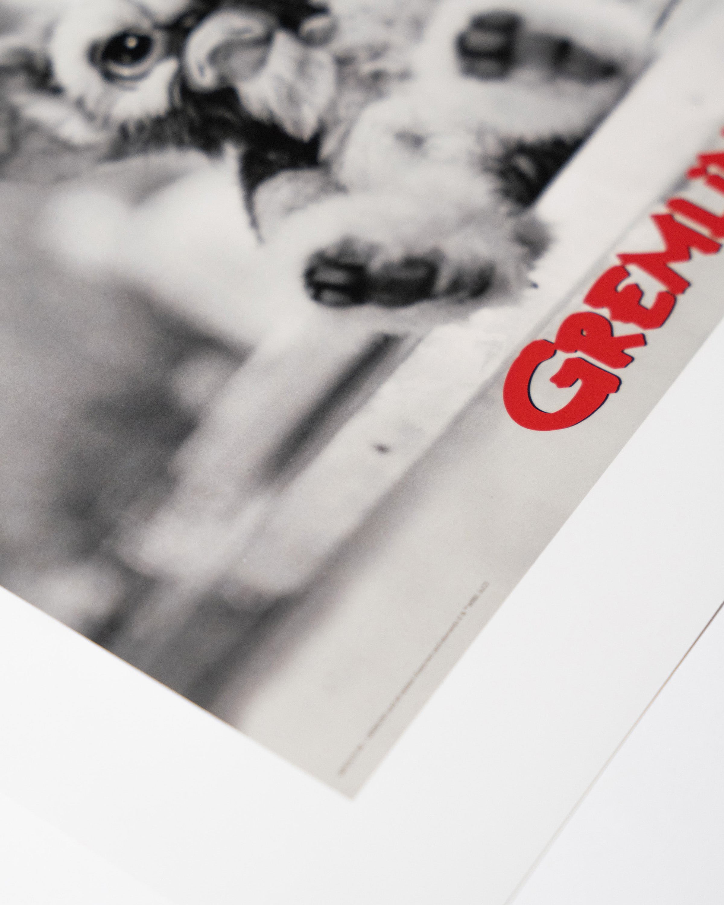 Detal plakatu Gremlins – zbliżenie na czerwony logotyp Gremlins na czarno-białej grafice