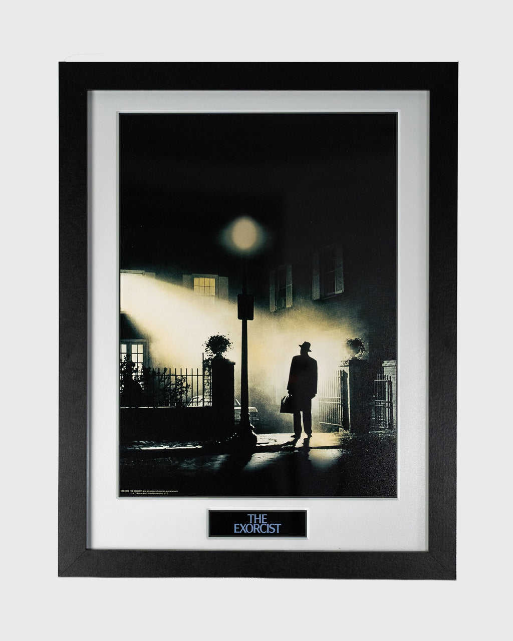 Plakat filmu The Exorcist przedstawiający postać księdza pod latarnią, czarna rama